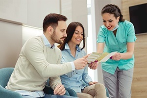 Dental team member showing paper work to man and woman
