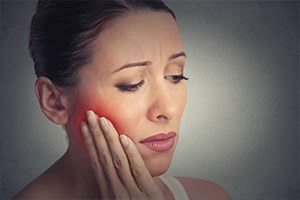 Woman holding cheek in pain
