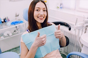 Woman in dental chair giving thumbs up