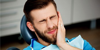 Dental patient holding his cheek in pain