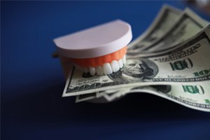 a model of teeth holding cash