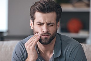 Man holding cheek in pain