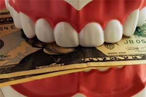 a model of teeth biting down on cash