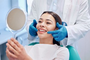 patient in a dental chair looking at their smile in a mirror 