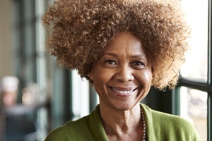 a person smiling and standing against a window