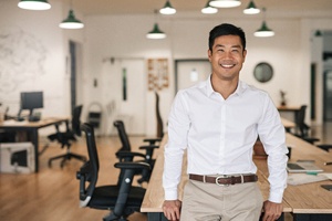 a smiling person resting against a desk