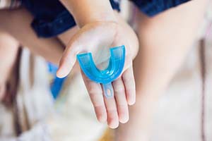 Outstretched hand holding a mouthguard for preventing dental emergencies