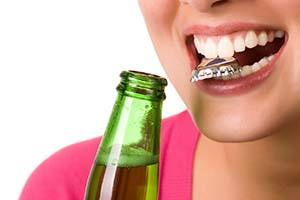 Woman holding bottlecap headed for dental emergency