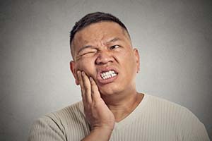 Pained man with toothache puts hand on cheek