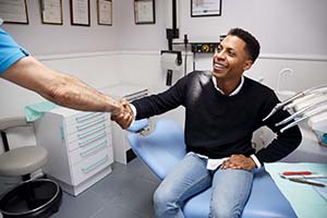 Patient and dentist shaking over cost of dental emergencies