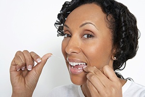 Woman practicing dental implant care in Dallas by flossing