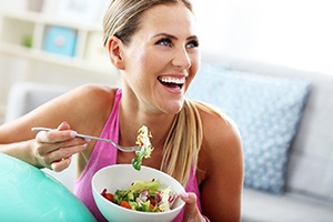 Woman eating a salad and smiling
