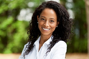 Older woman with dental implants in Dallas smiling outside.