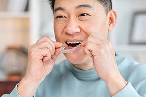 a man smiling and putting Invisalign trays in his mouth