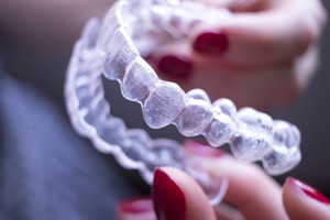 A person holding an Invisalign aligner