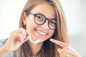 Smiling girl pointing to her Invisalign in Dallas