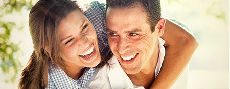 Smiling man and woman holding each other outdoors