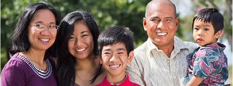 Mother father and three children smiling together outdoors