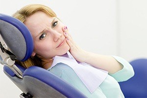 Woman in dental chair holding cheek