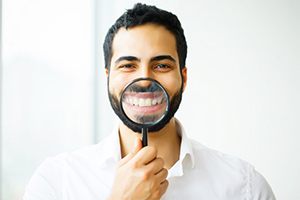 man holding magnifying glass in front of his smile