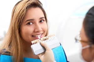 dentist holding a row of veneers up to a patient’s smile