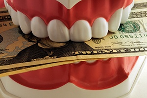 a model of the mouth biting down on a stack of money