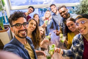 a group of friends taking a selfie together while getting drinks at a local restaurant