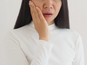 a person holding their mouth because their cheek is swollen