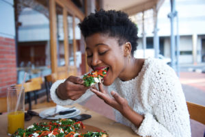 person sitting outside and eating a piece of pizza