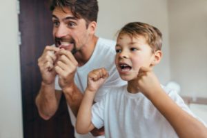 a father and son flossing their teeth together 