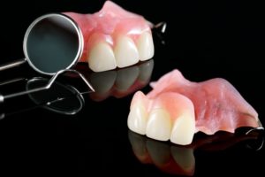 partial dentures sitting next to a dental mirror