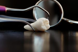 an extracted tooth and a dental mirror