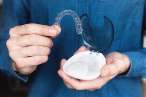 a person holding Invisalign clear aligners 