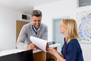 a patient speaking with a front desk dental worker