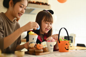 a parent baking Halloween treats with her child