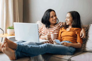 a mom and her daughter sitting on a couch smiling together